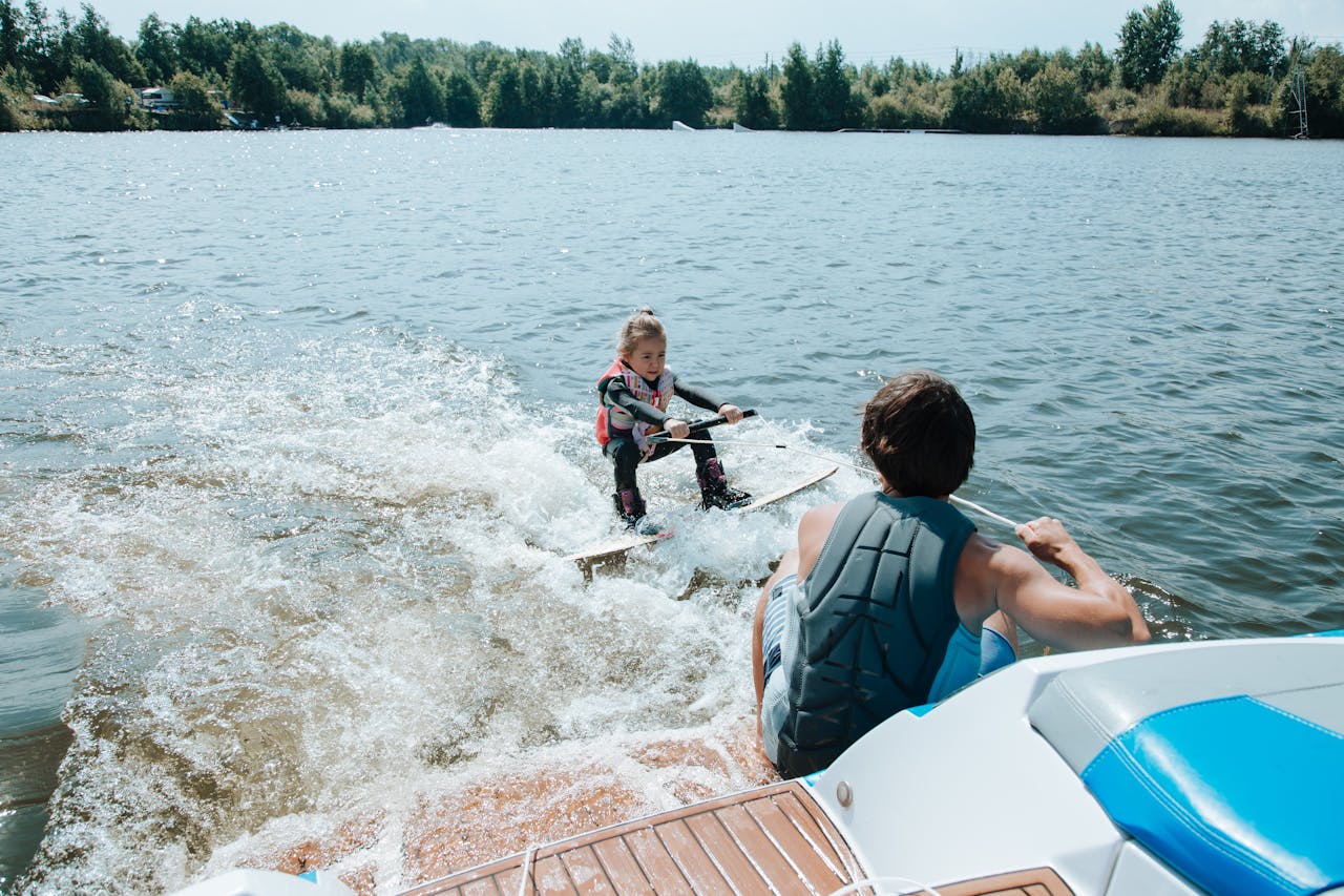 Father and daughter enjoying wakeboarding on a sunny day by the lake.