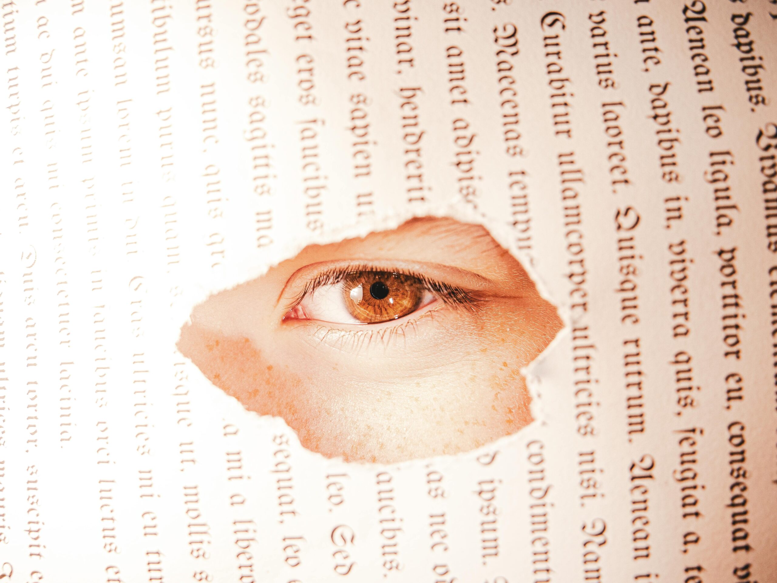 PARLARE DEL PROBLEMA NON BASTA A close-up of an eye seen through a torn book page, creating a conceptual visual.